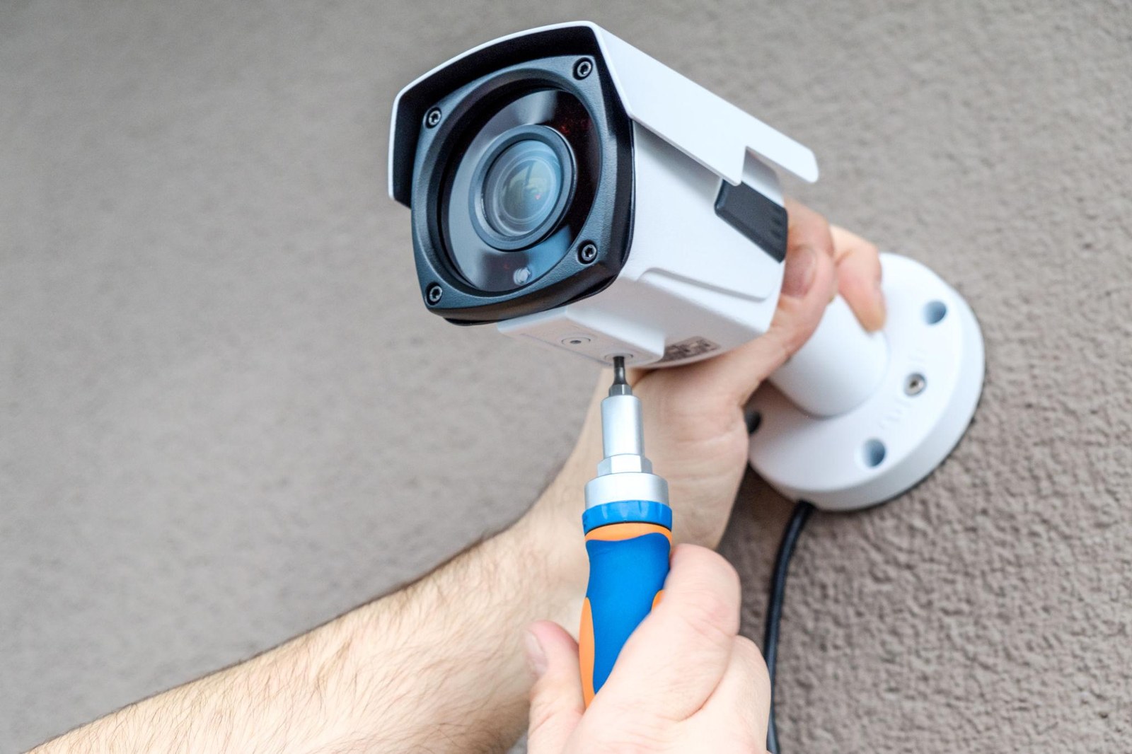 Engineer fitting a CCTV bullet camera to a wall in Ealing