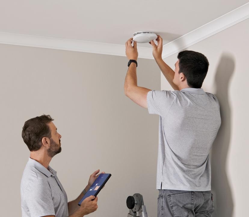 Two engineers fitting a ceiling Wi-Fi access point